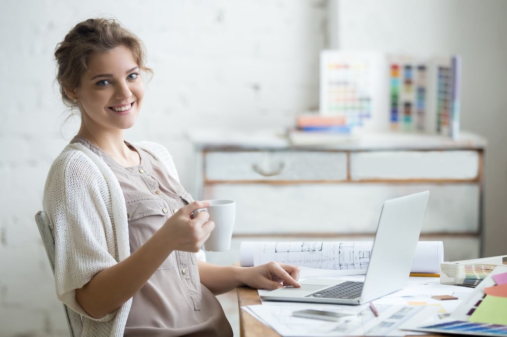 woman holding a coffee cup in front of a computer