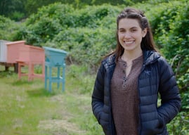 Emma Egstad (Bee and Bloom) with bee hives in the background