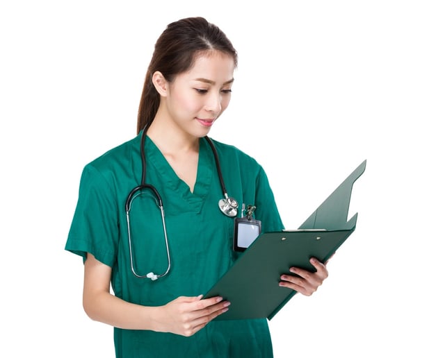 Medical staff member with green scrubs and a stethoscope holding a chart